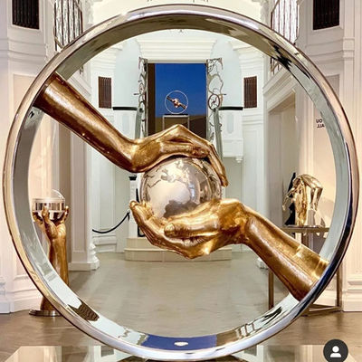 La mano ha lucidato l'acciaio inossidabile dello specchio che custodice le sculture della terra